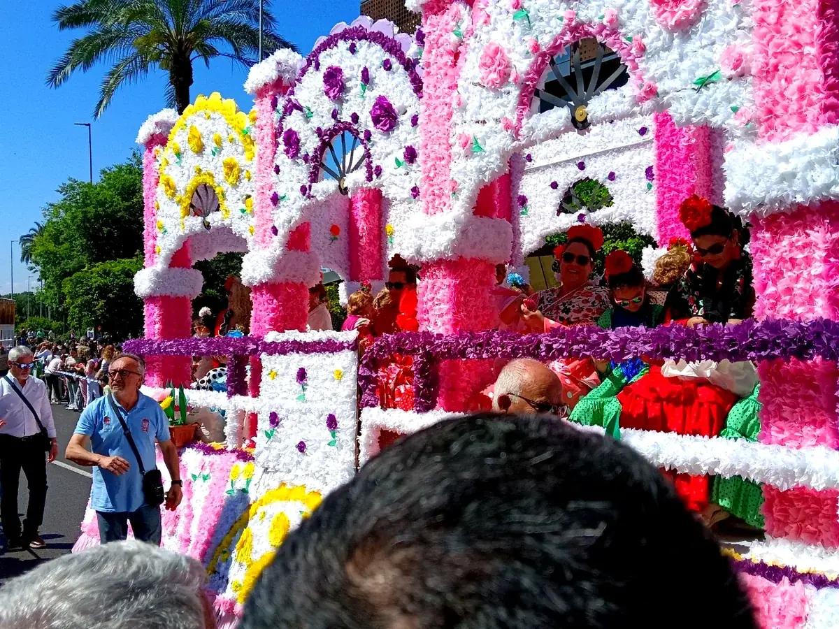Mujeres con vestido de flamenca en una carroza rosa de la Batalla de las Flores