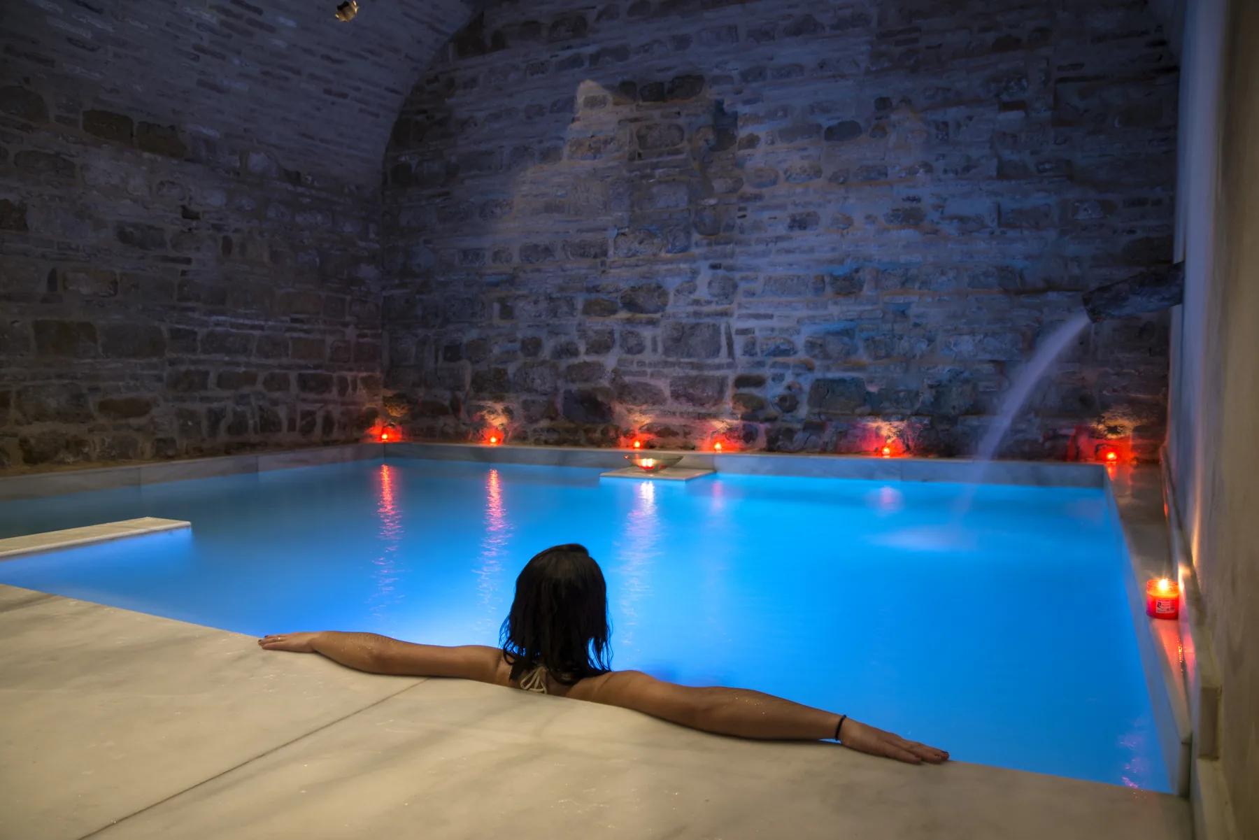 Pessoa a flutuar numa piscina turquesa com velas